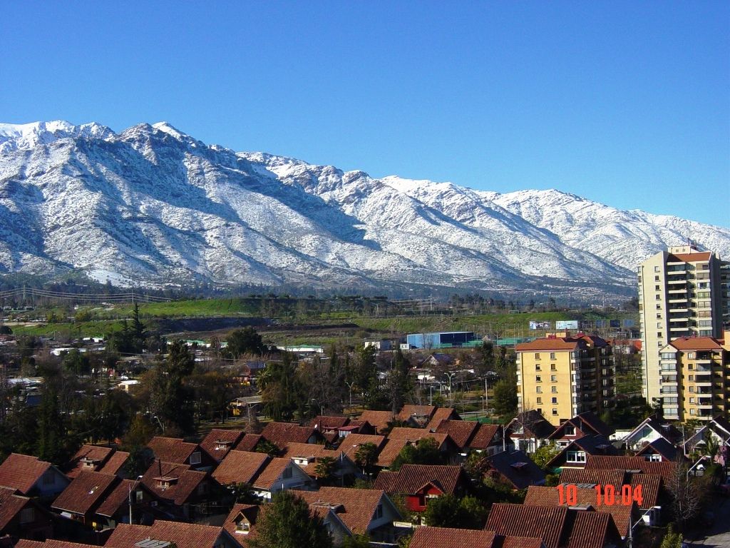 Snow-covered Andes range rising directly behind the rooftops and apartment blocks of eastern Santiago