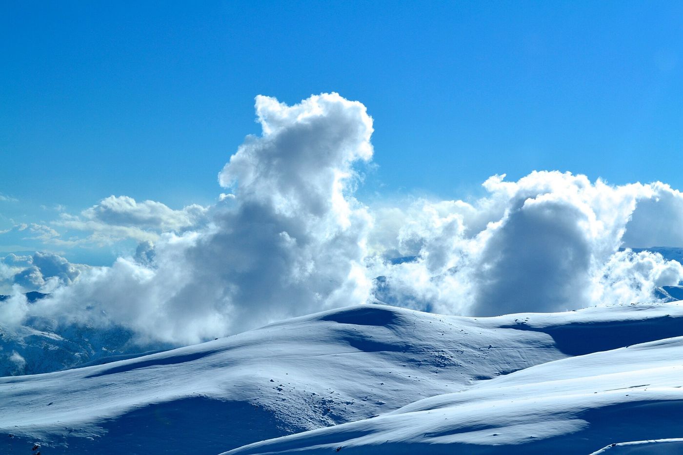 Snow-covered slopes of La Parva in the Chilean Andes under towering cumulonimbus clouds