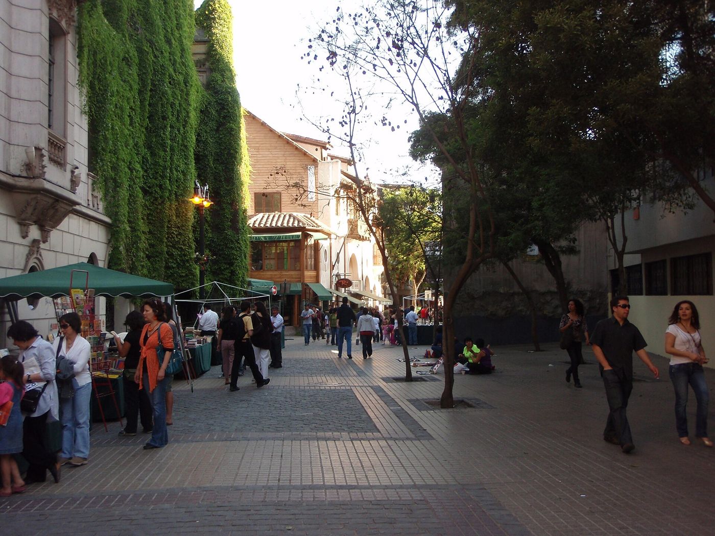 Pedestrian street in Barrio Lastarria with market stalls, trees and people walking