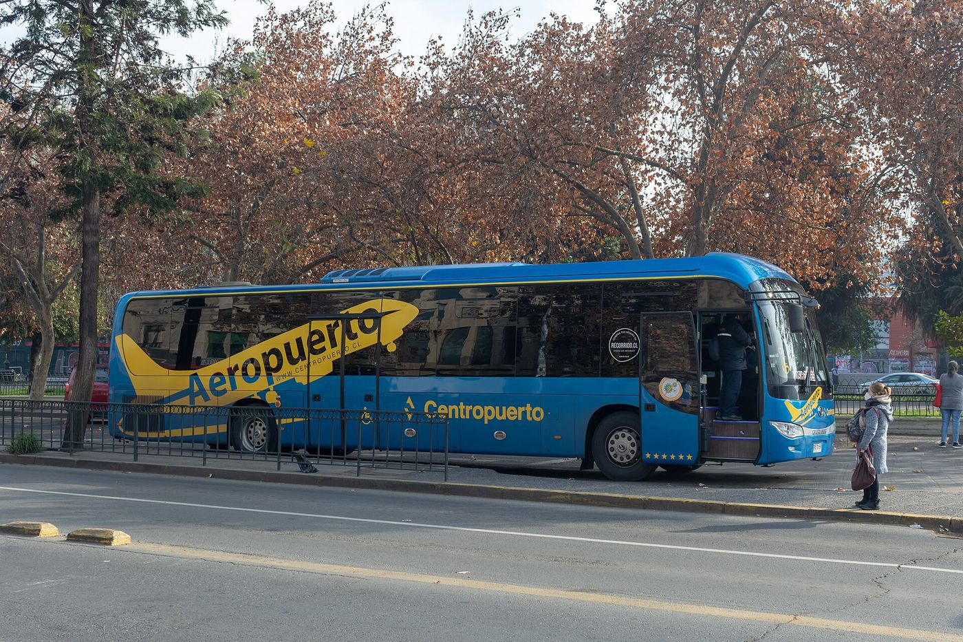 Blue and yellow Centropuerto airport bus waiting at a kerb in Santiago