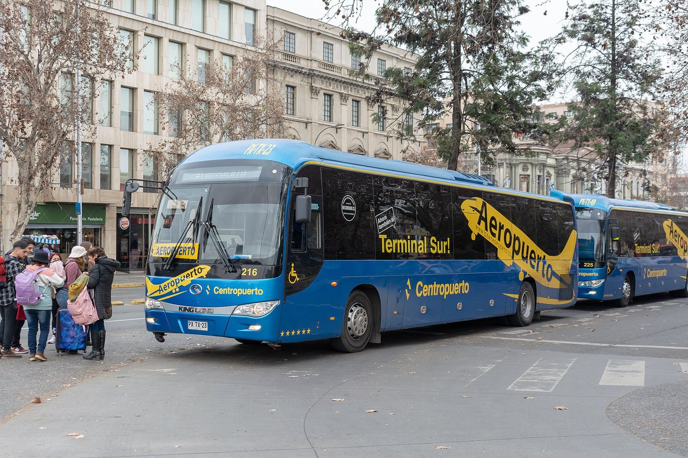 Passengers with luggage boarding Centropuerto buses at the Los Heroes stop in central Santiago