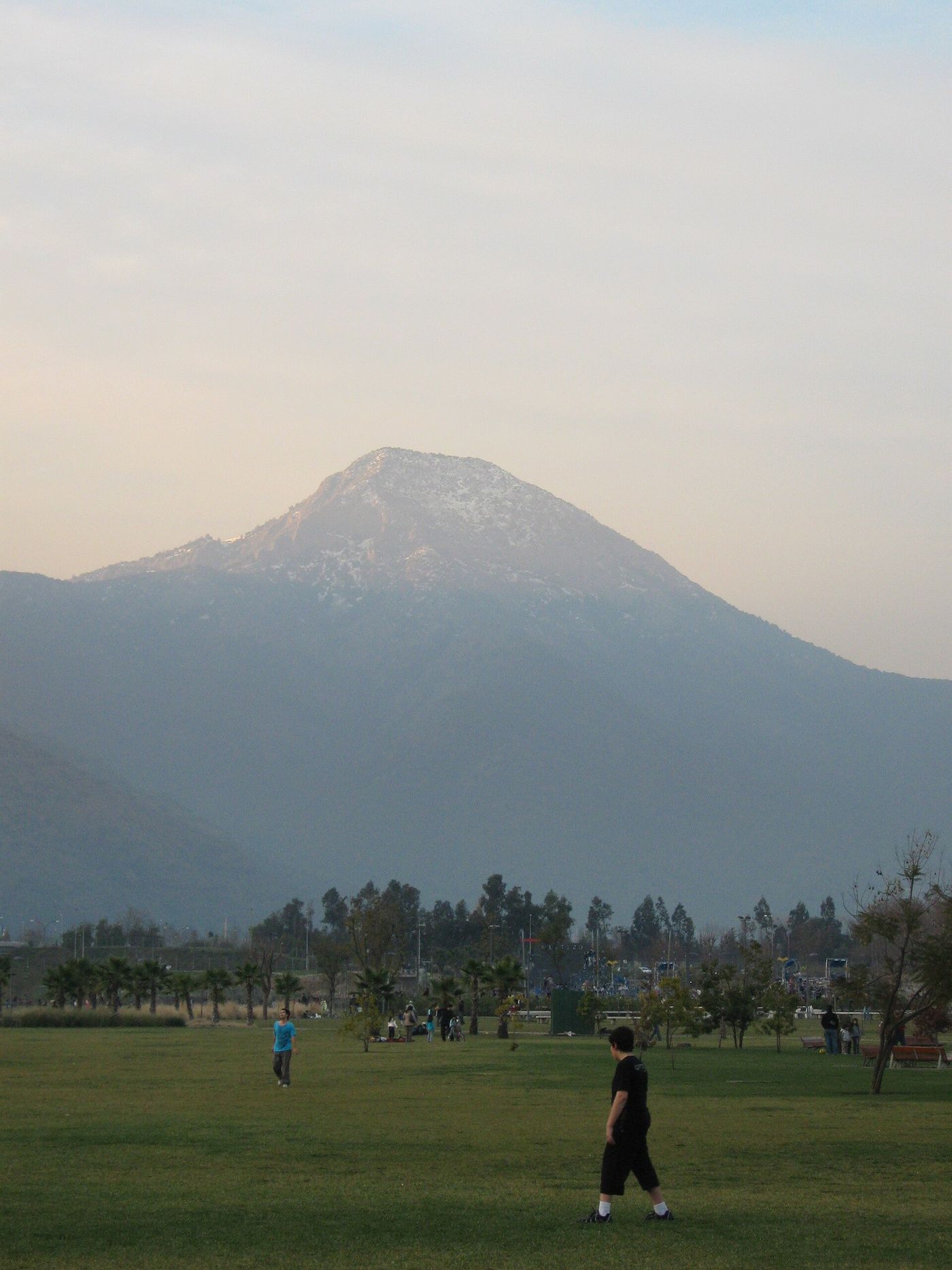 Cerro Manquehue seen hazily above a green park in eastern Santiago, its pointed summit dominating the skyline