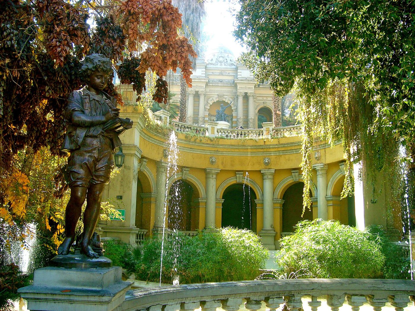 Ornate yellow terrace and fountain on Cerro Santa Lucía framed by autumn trees and a bronze statue