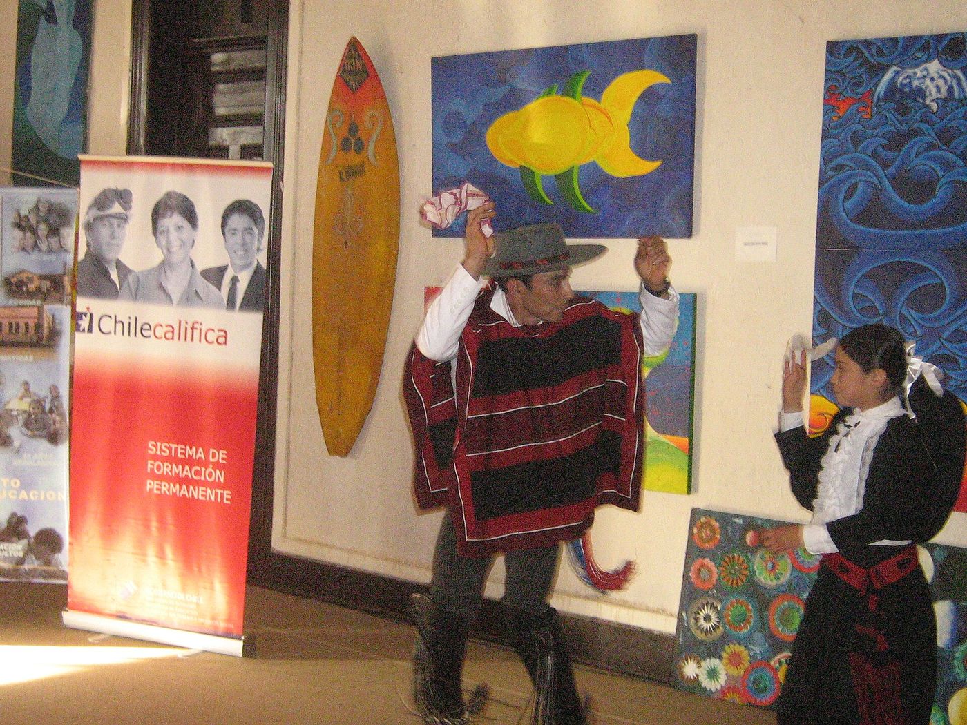 A huaso in a poncho and hat dancing the cueca with a partner, handkerchiefs raised