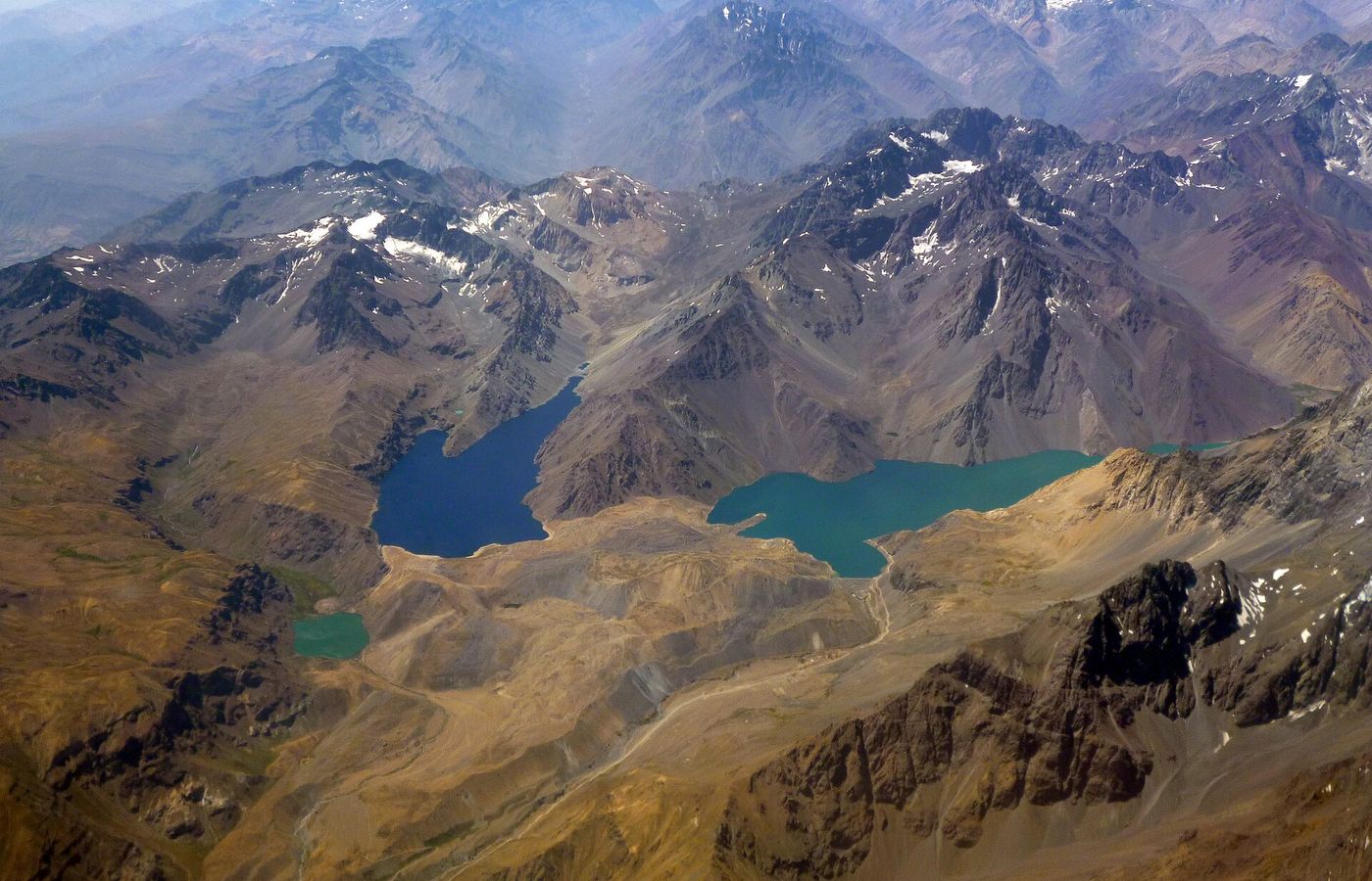 Turquoise water of Embalse El Yeso and Laguna Negra seen from above, ringed by bare Andean mountains