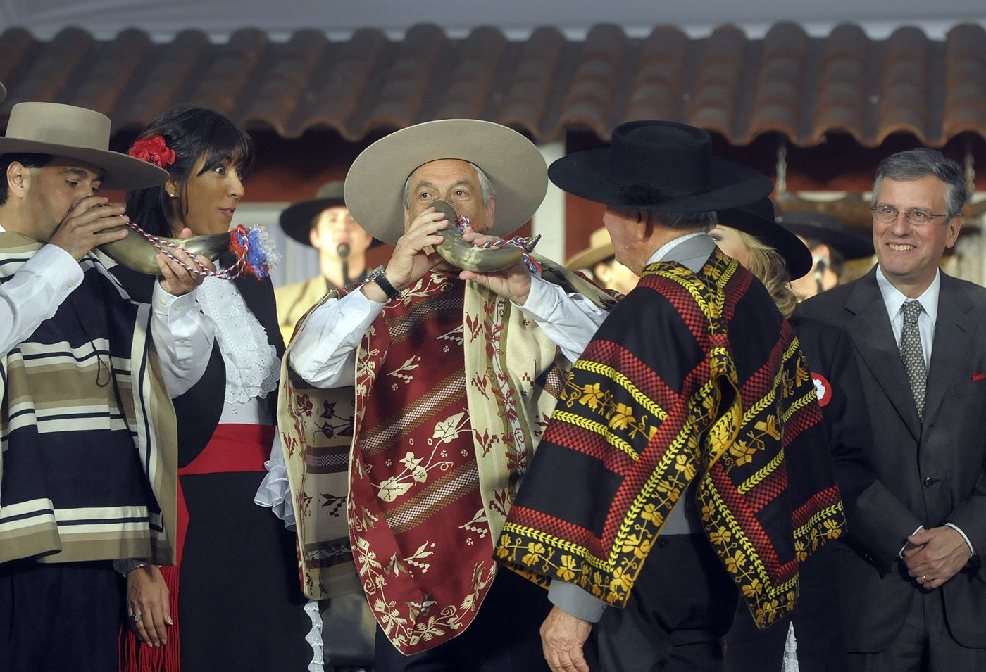 Chilean huasos in traditional striped ponchos and wide-brimmed hats playing instruments at a Fiestas Patrias event
