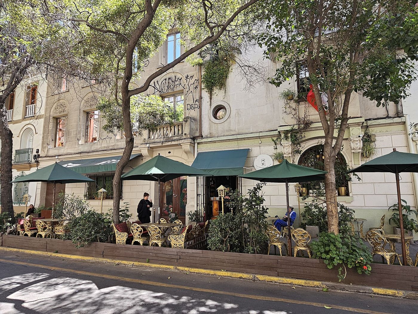 Restaurant terraces shaded by trees on a street in Barrio Lastarria, Santiago