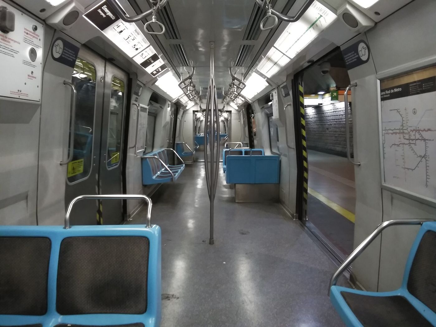 Empty interior of a Santiago Metro train carriage with blue seats and grab poles