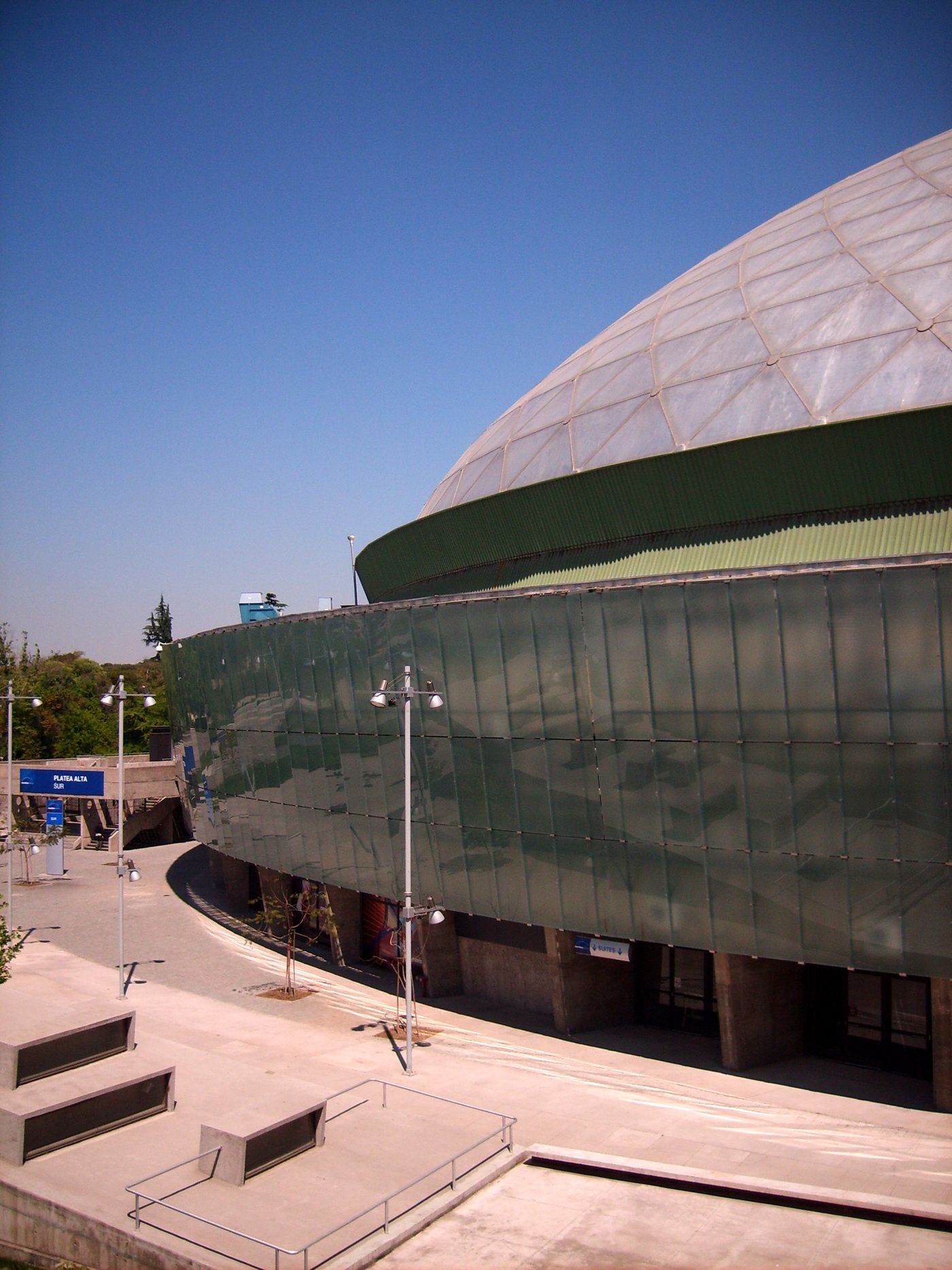 The green glass and concrete exterior of the Movistar Arena in Parque O'Higgins, Santiago