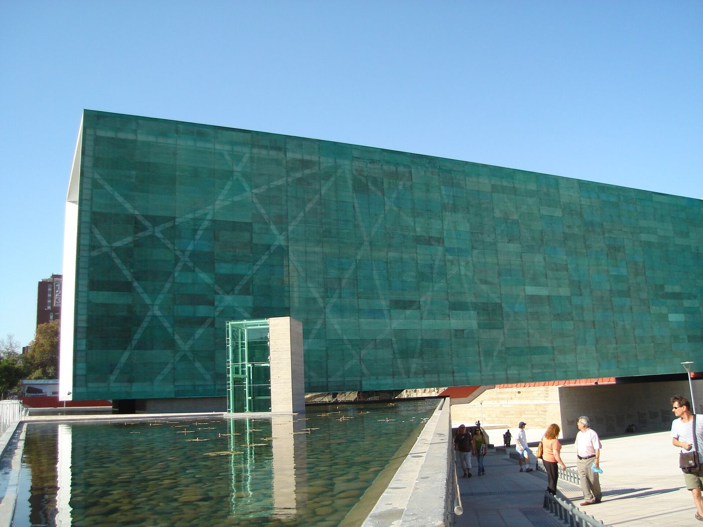 Green glass and copper exterior of the Museo de la Memoria y los Derechos Humanos beside a reflecting pool