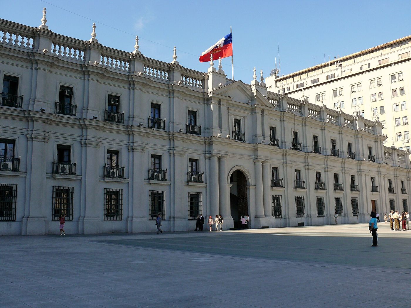 Neoclassical white facade of Palacio de La Moneda with the Chilean flag flying above the entrance