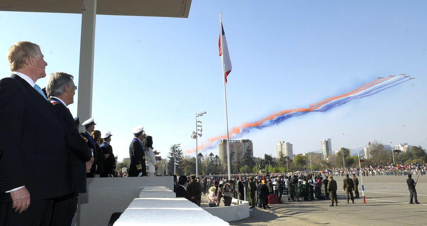 Aircraft trailing red, white and blue smoke over the Parada Militar parade ground in Parque O'Higgins, Santiago