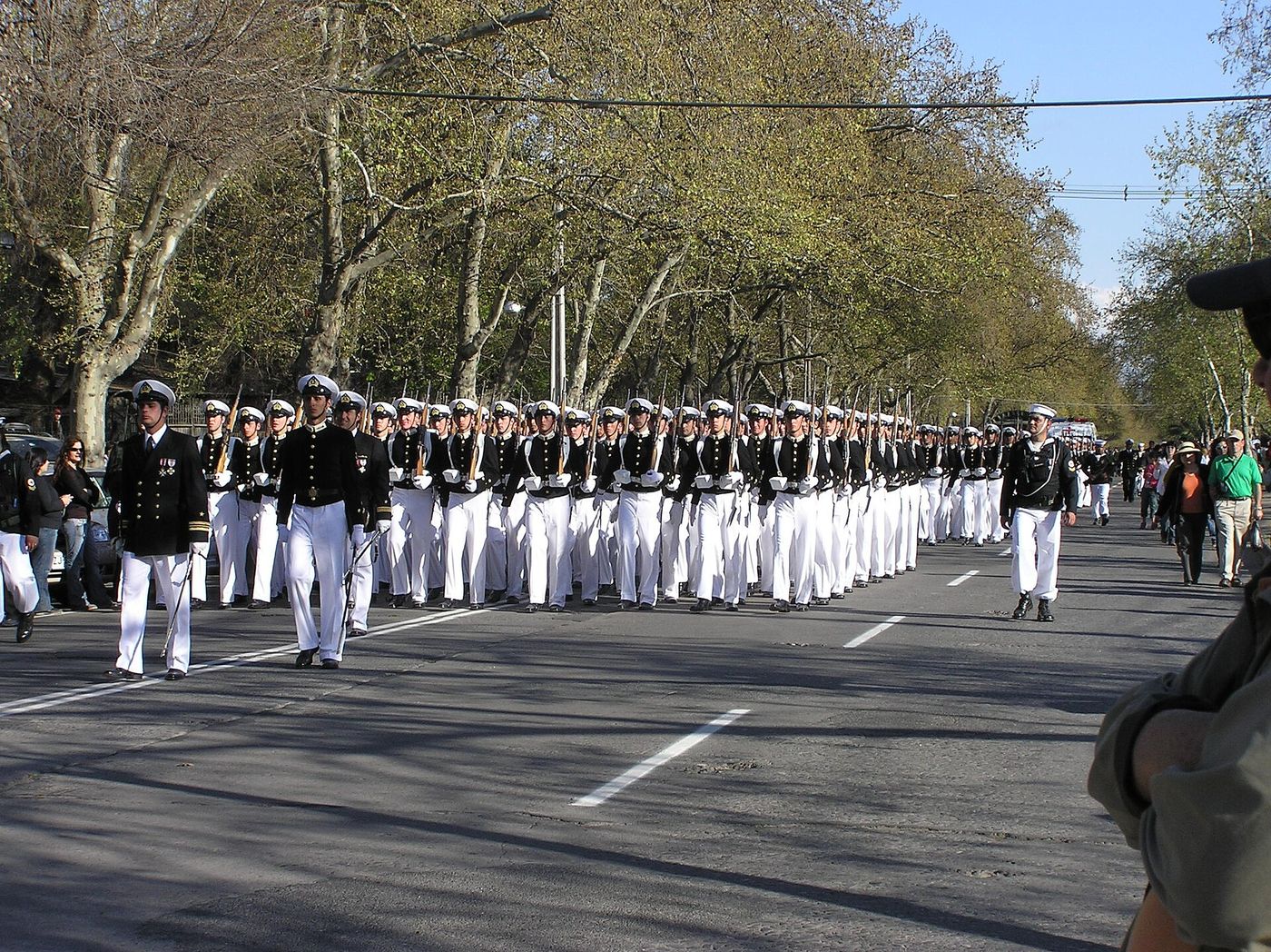 Uniformed ranks marching along a tree-lined avenue inside Parque O'Higgins in Santiago