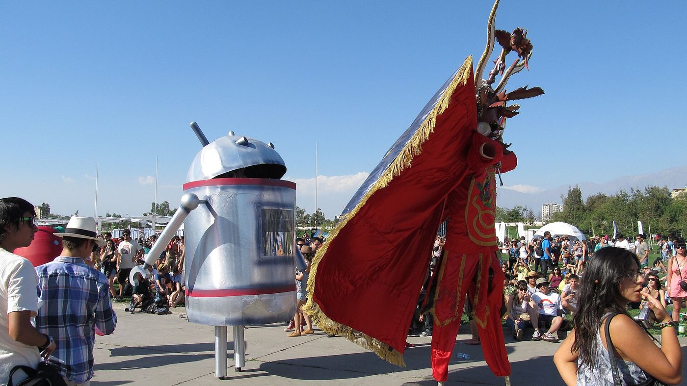 Costumed performer in a red cape moving through a daytime festival crowd at Lollapalooza Chile