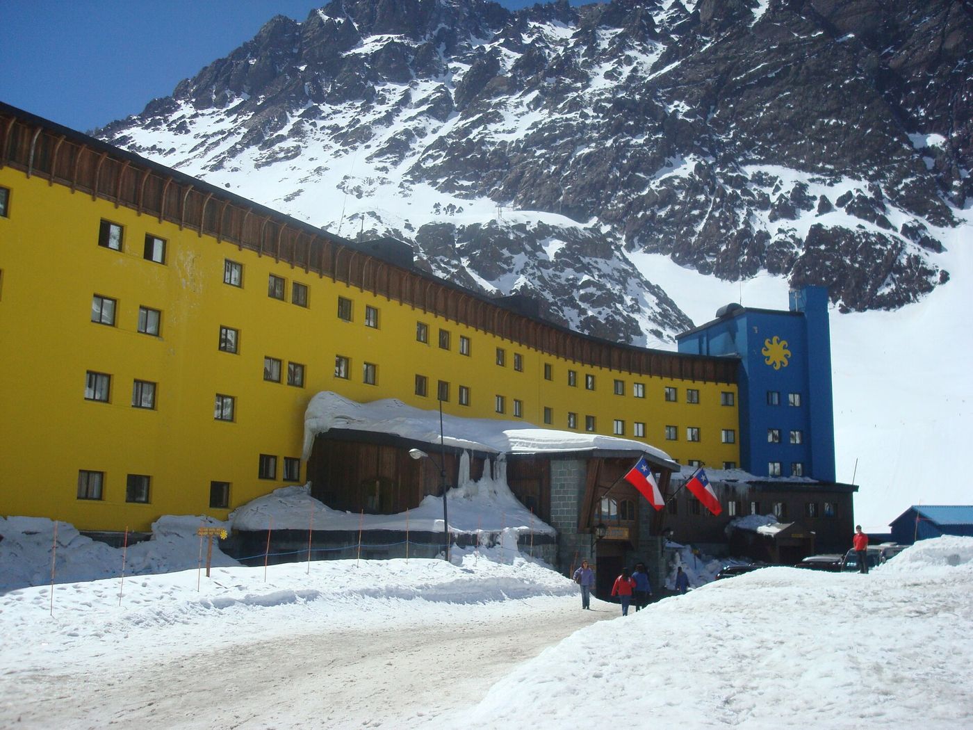 The bright yellow Hotel Portillo standing in deep snow beneath steep Andean peaks in Chile