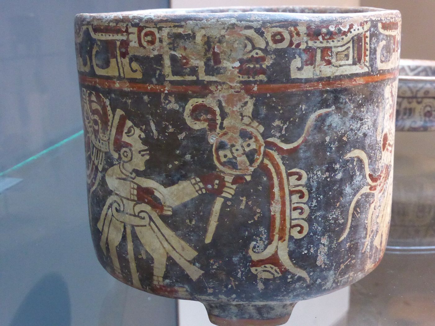 Painted Maya-Ulua ceramic tripod vessel with figures, displayed at the Precolombino museum in Santiago