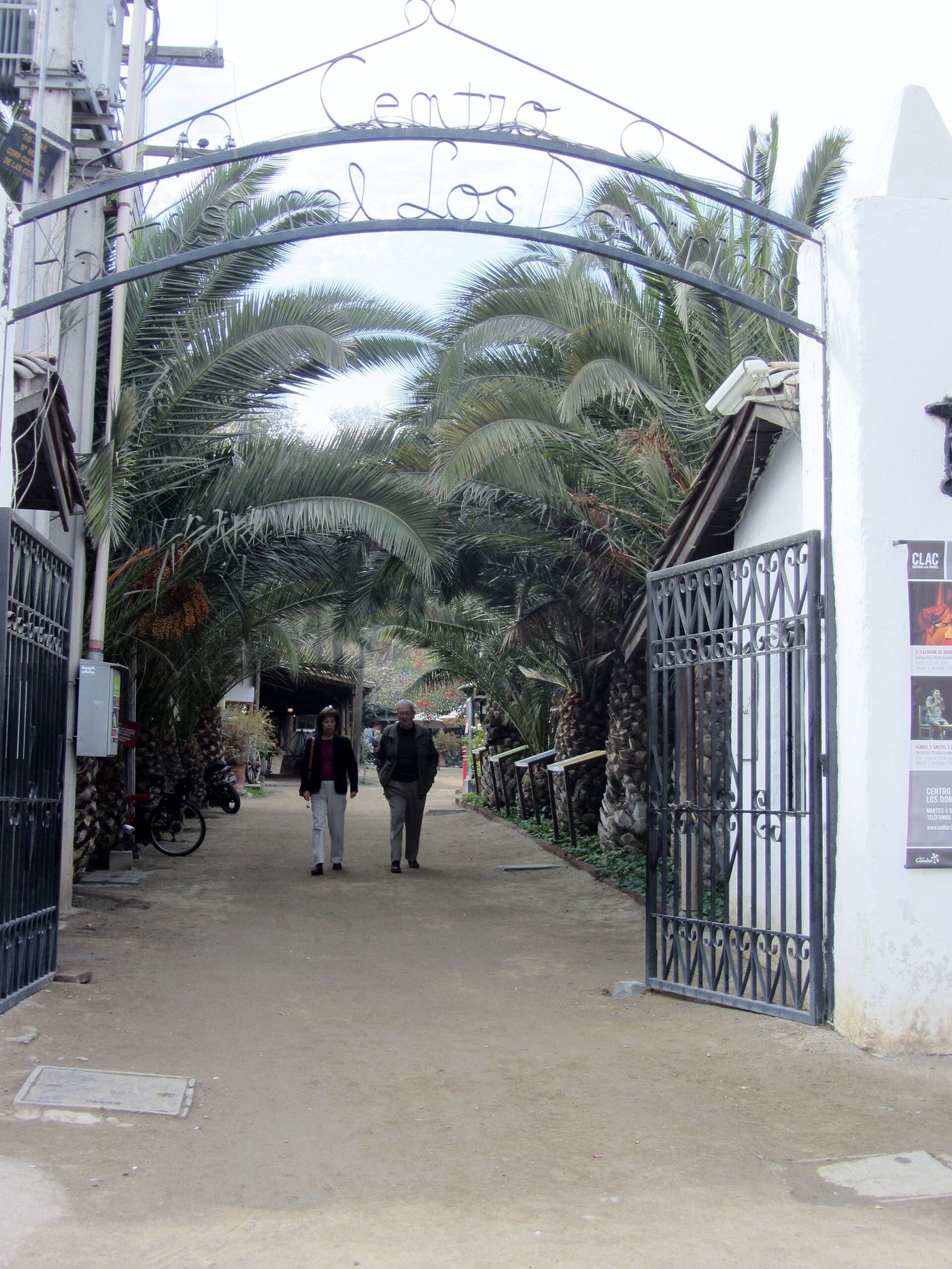 Wrought-iron gateway into the Pueblito Los Dominicos craft village in Las Condes, Santiago, with palm trees beyond