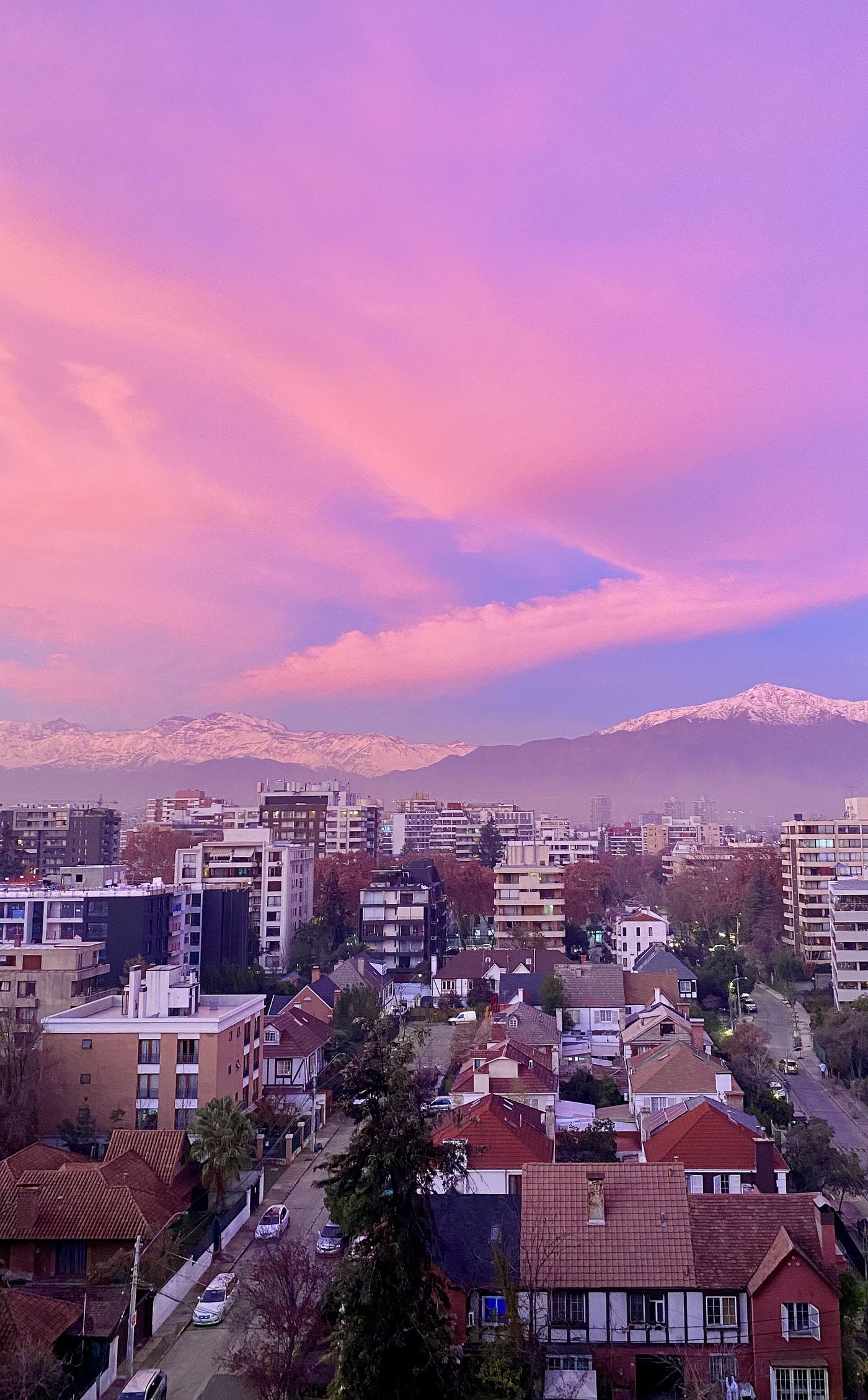 Winter sunset over Santiago rooftops with snow-covered Andes peaks on the horizon