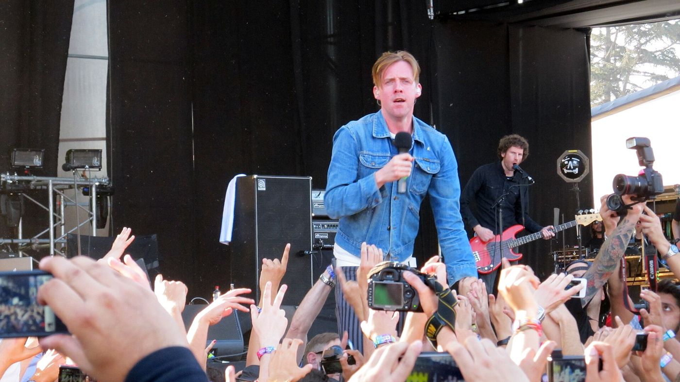 Singer at the front of a stage with the crowd's hands and phones raised at Lollapalooza Chile