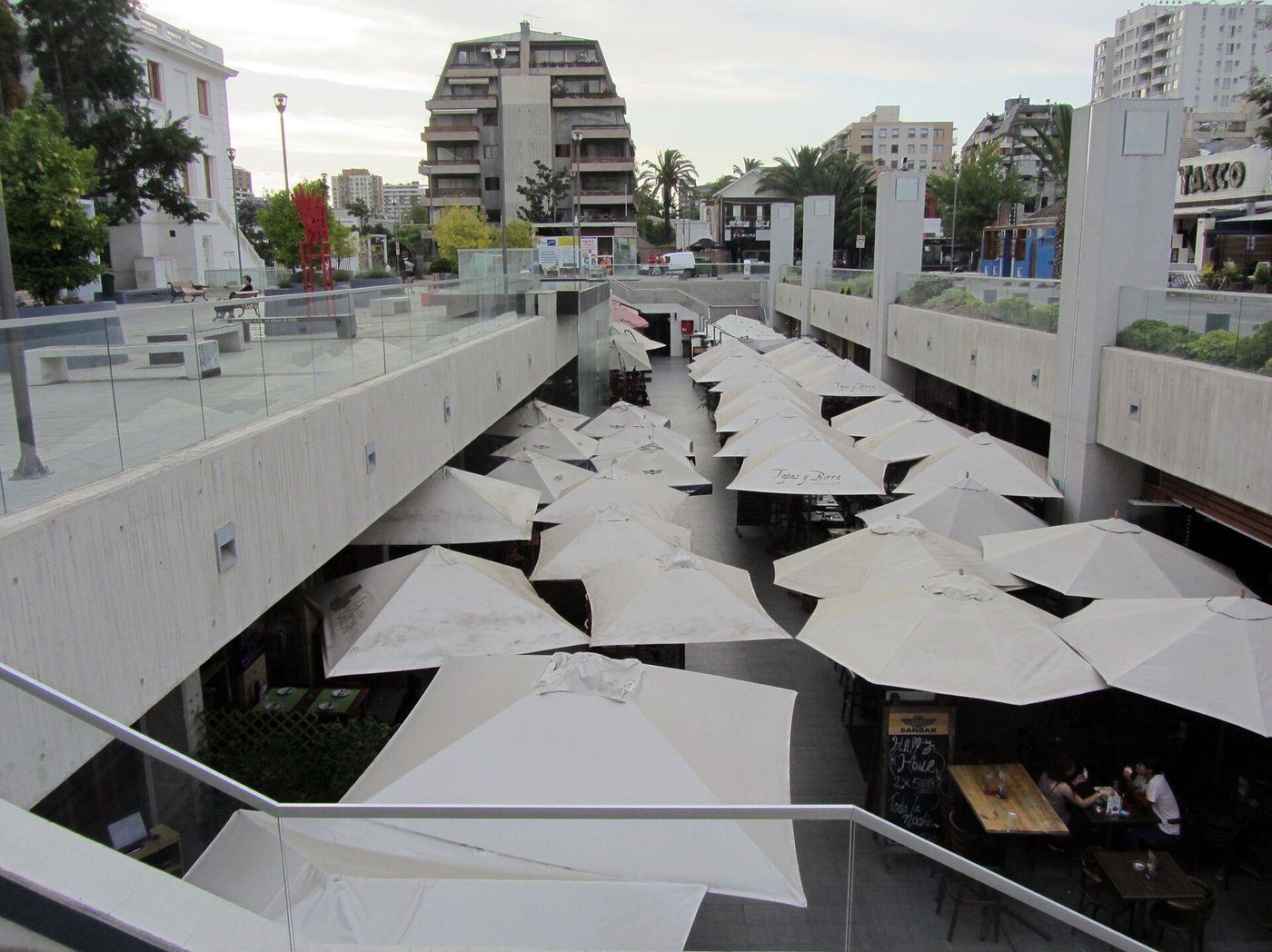 White parasols over restaurant terraces on the lower level of the Plaza Nunoa boulevard in Santiago