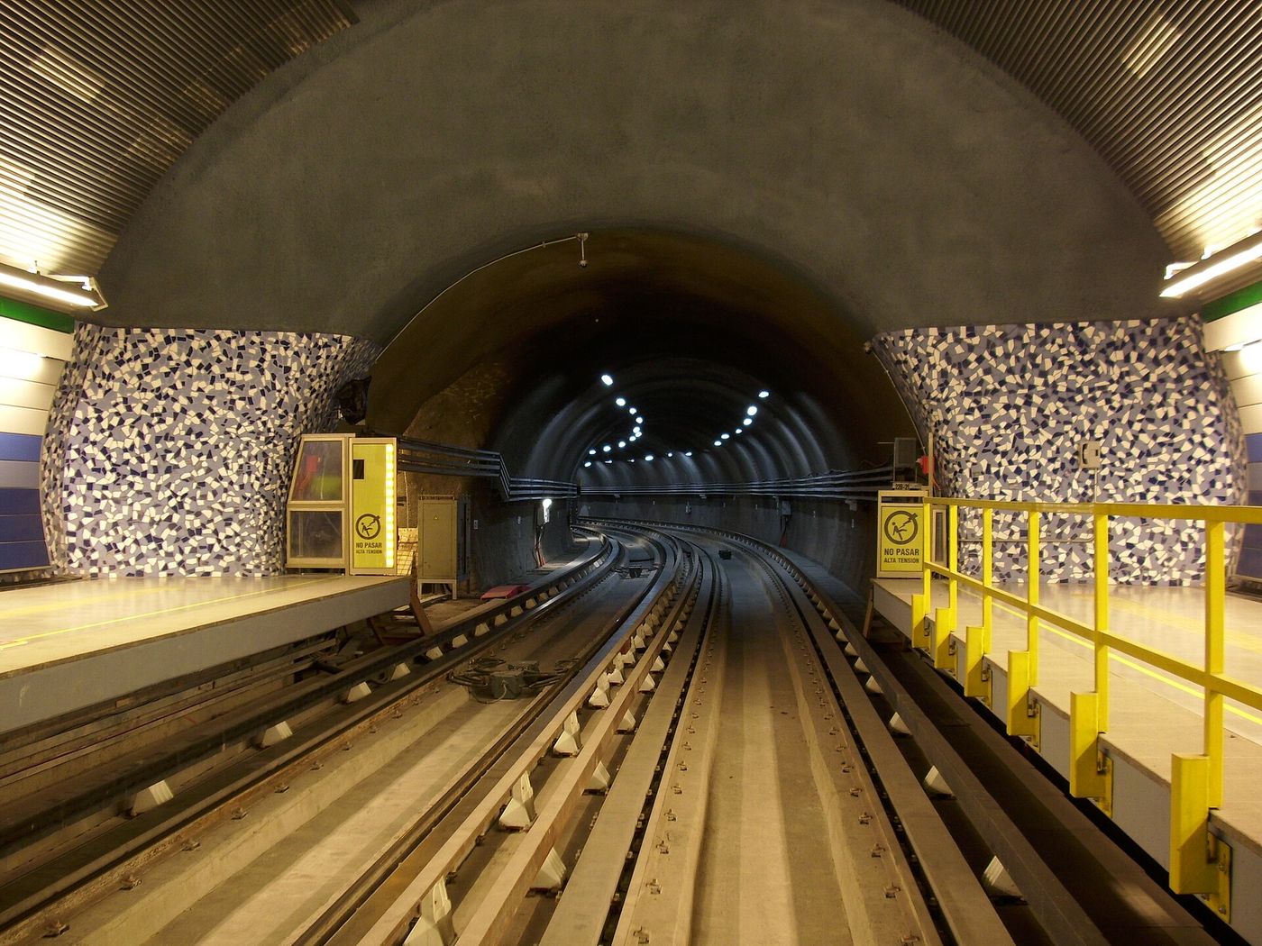 Platform edge and track inside a Santiago Metro station, with yellow safety barriers along the platform
