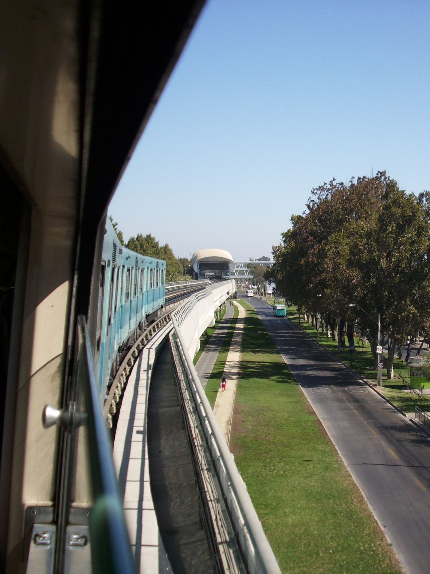 Santiago Metro track running on an elevated viaduct beside a tree-lined avenue