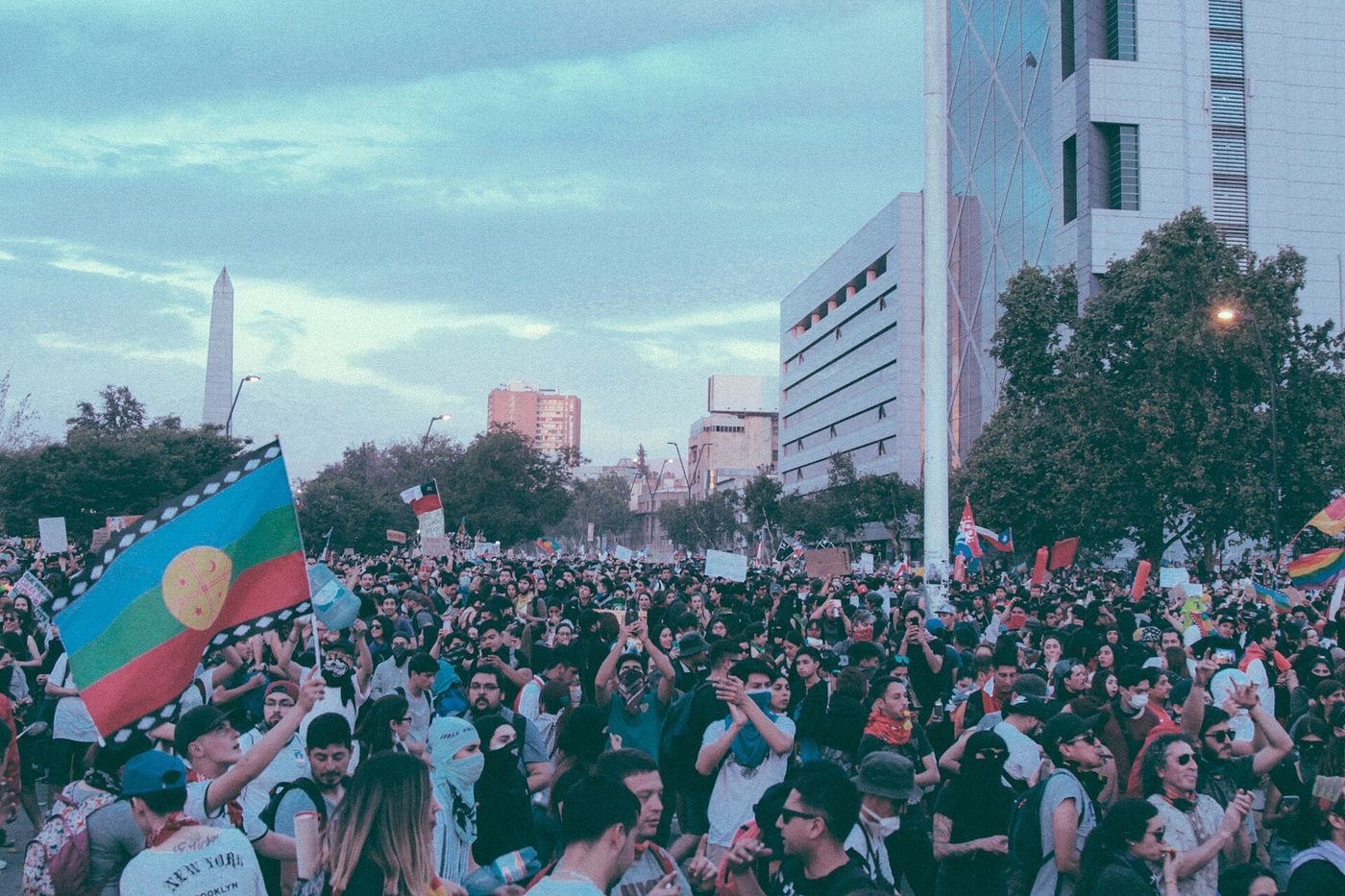 Large crowd of demonstrators filling an avenue in Santiago with flags raised
