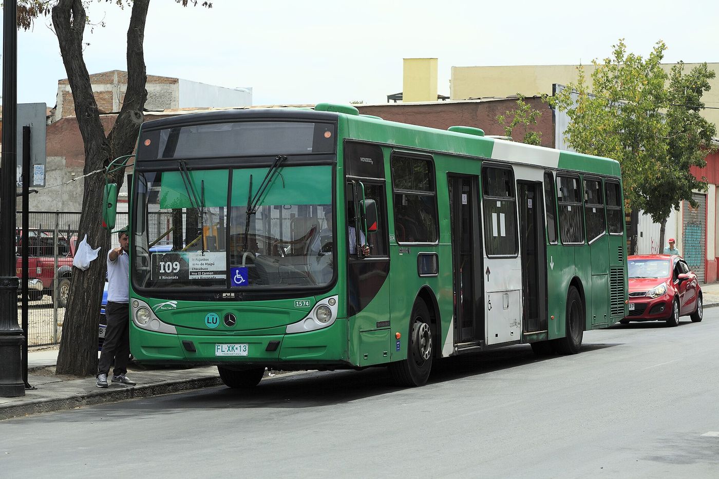 Green RED bus picking up passengers on a Santiago street lined with trees