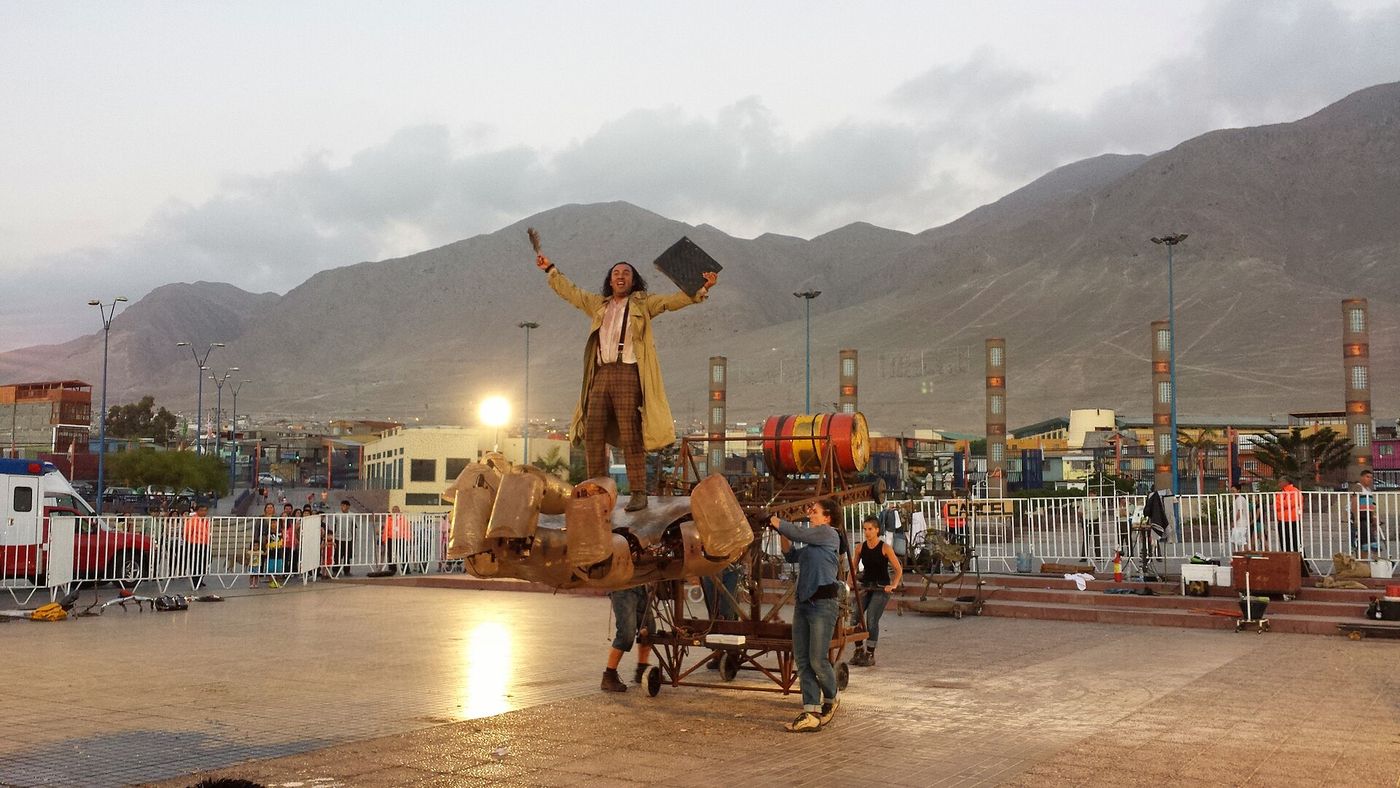 Performers raising a giant puppet figure during an outdoor street theatre production in Chile