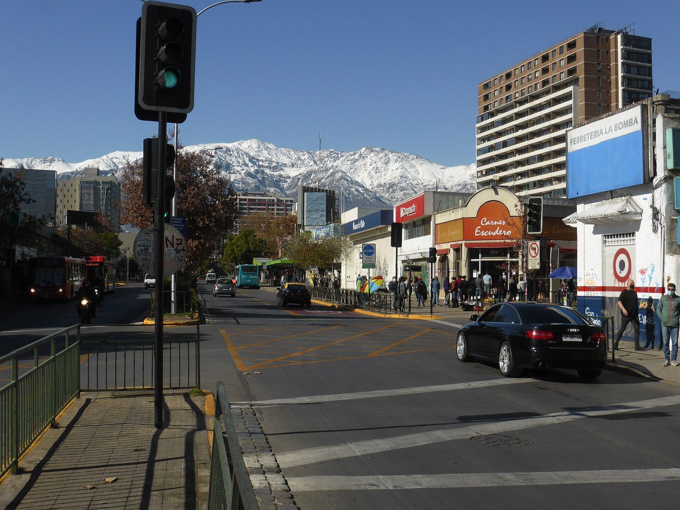 A Santiago street with traffic and shopfronts and the snow-covered cordillera filling the view at the end of it