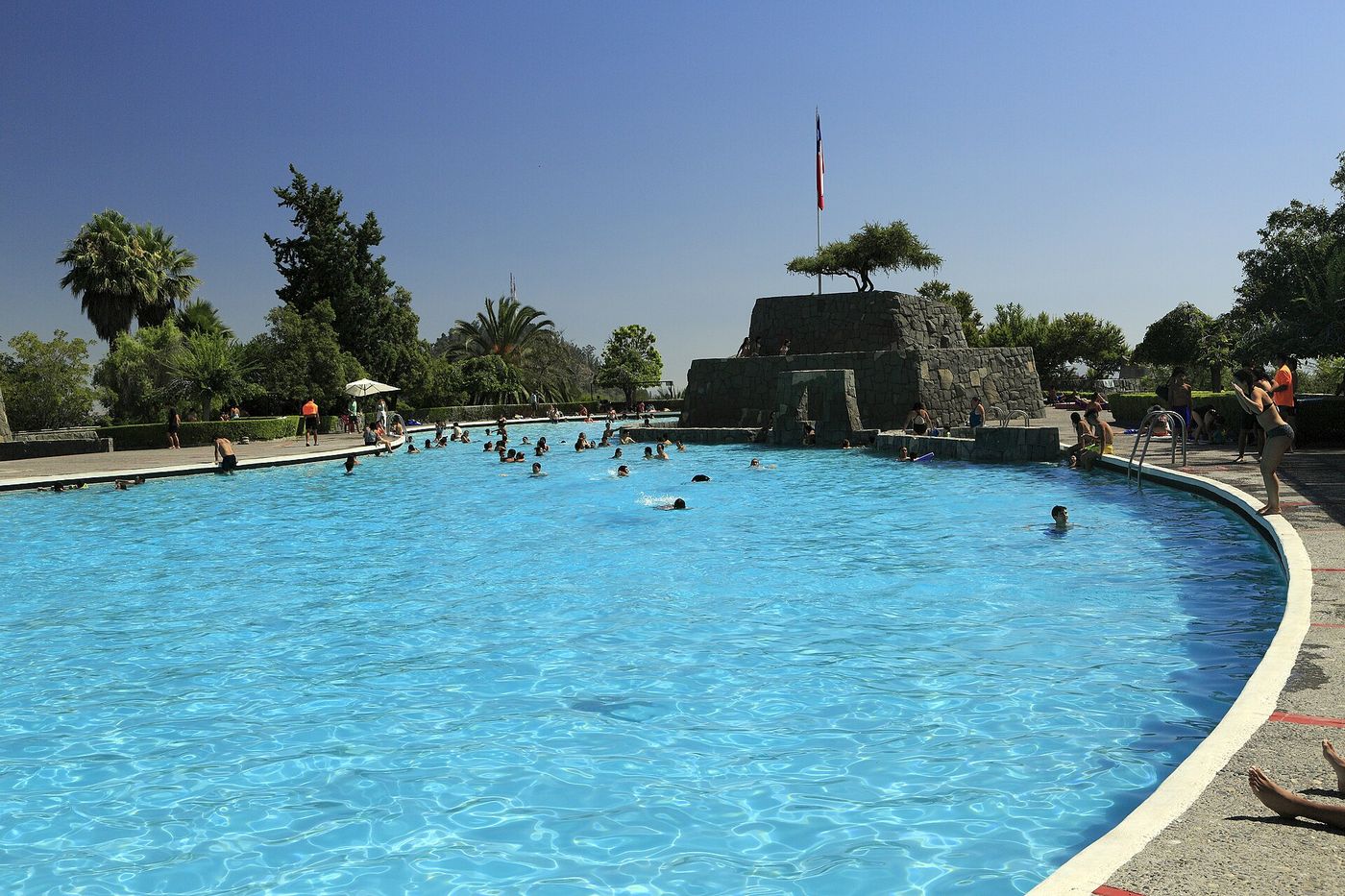 Swimmers in the blue open-air Piscina Antilen pool on Cerro San Cristobal in Santiago