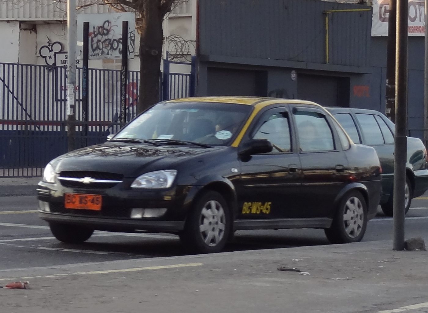 A black Santiago taxi with a yellow roof parked at the kerb on a city street