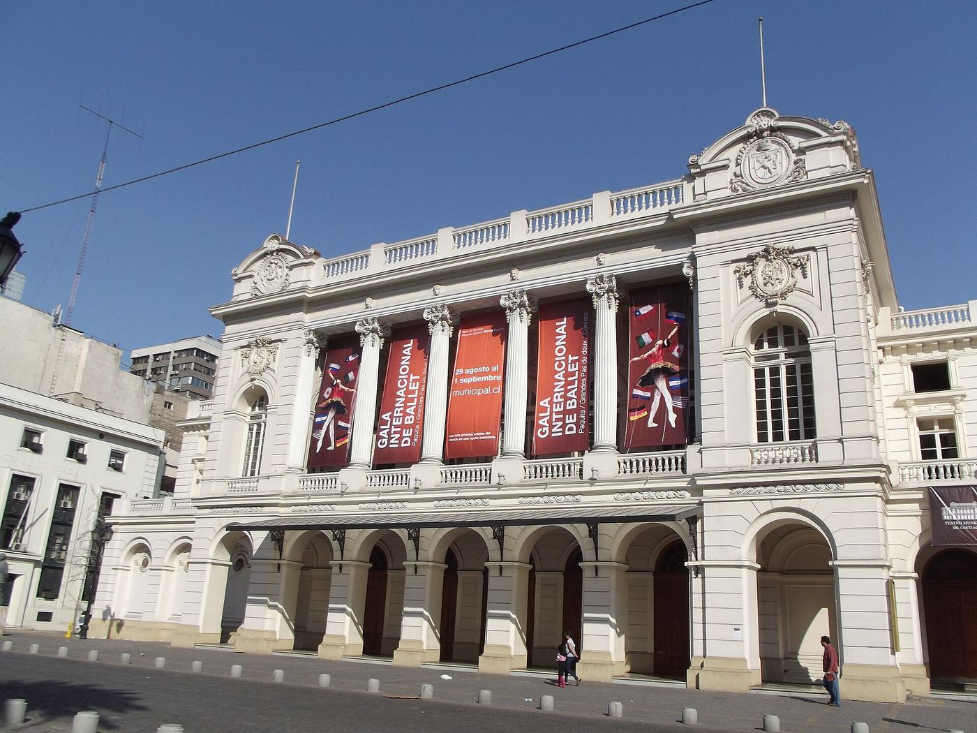 The neoclassical facade of the Teatro Municipal de Santiago with season banners hanging between its columns