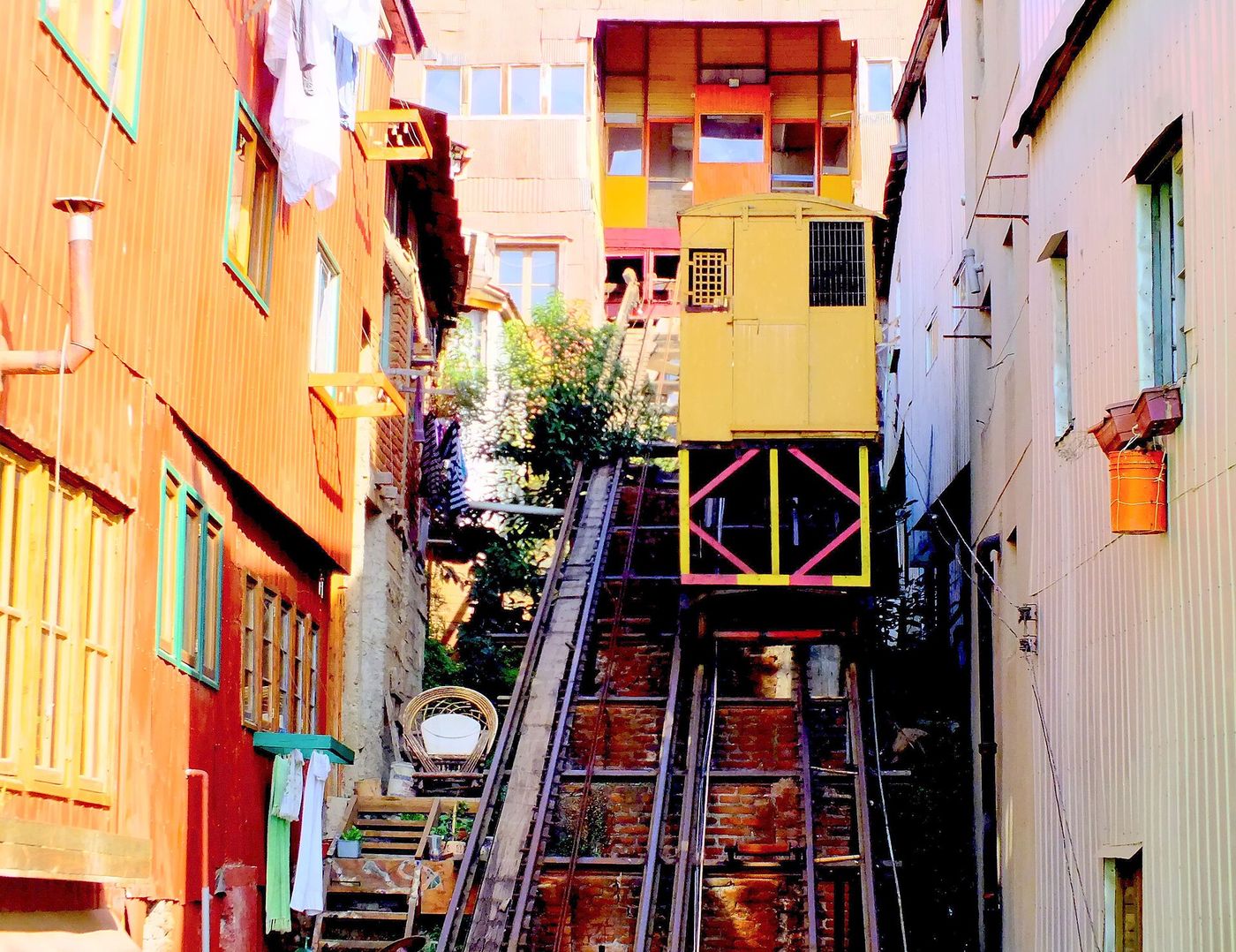 A funicular car climbing between brightly painted houses on a Valparaiso hillside