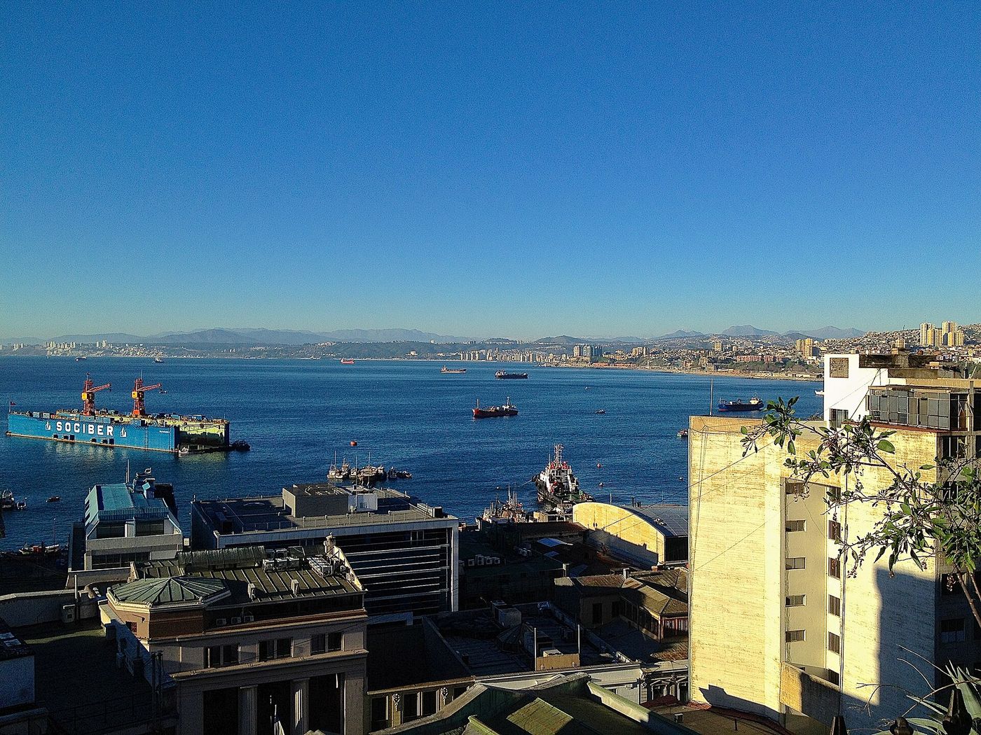 Ships in the bay below the hillside buildings of Valparaiso on a clear summer day