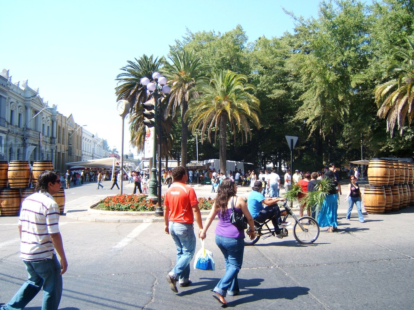 Wine barrels and stalls lining a street during a Chilean vendimia grape harvest festival, with families walking between them