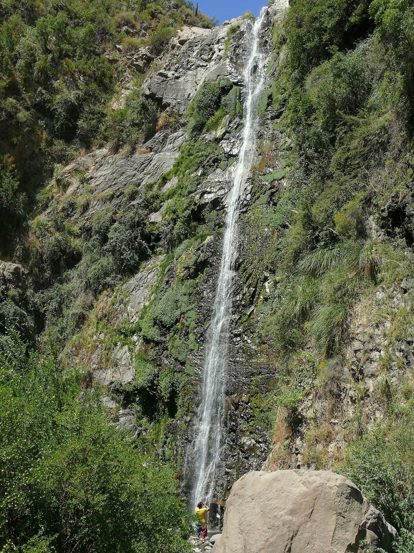 A tall thin waterfall dropping down a green rock face at the Cascada de las Ánimas sanctuary