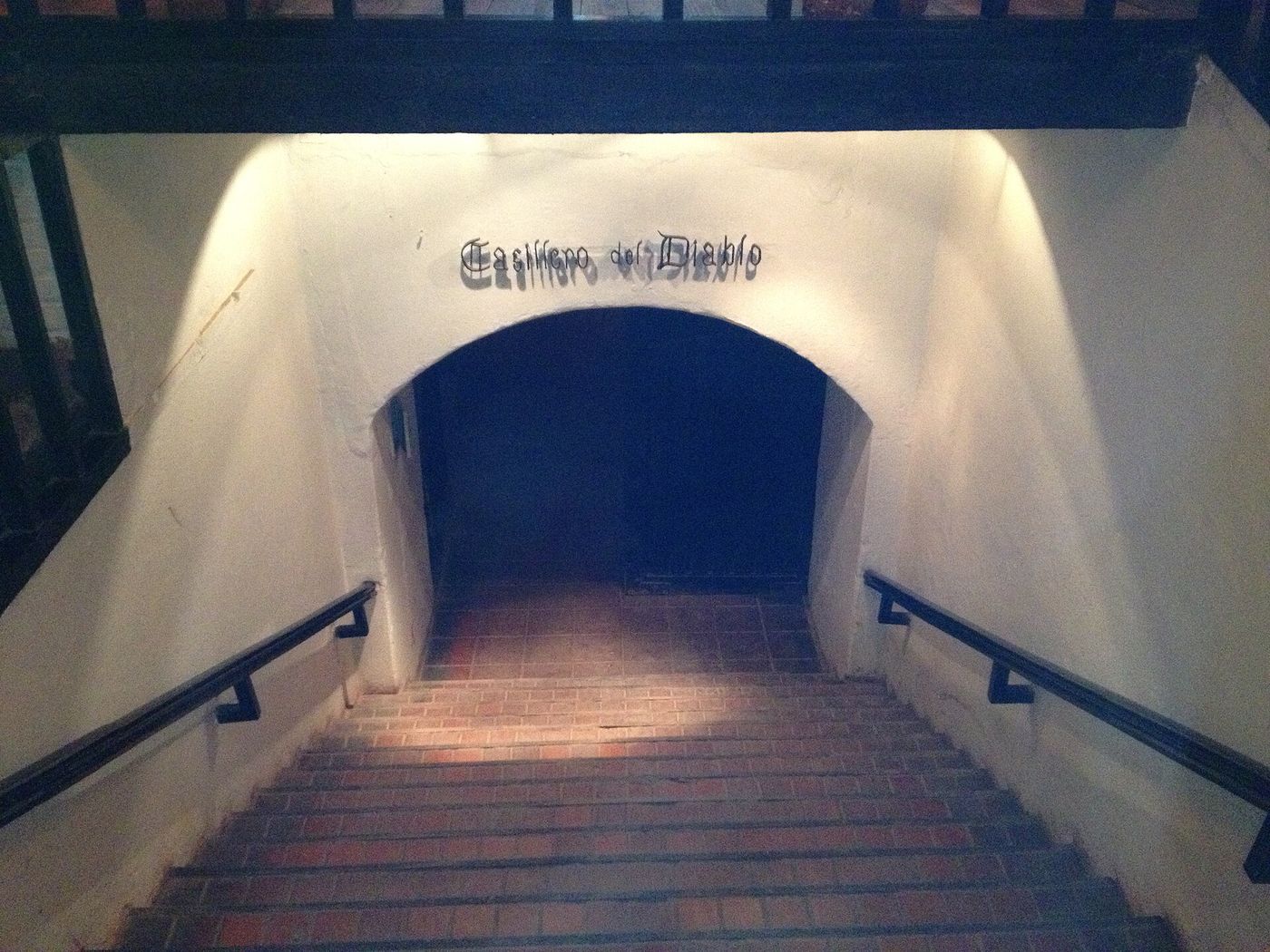 A flight of stone steps leading down through a whitewashed arch into the Casillero del Diablo cellar at Concha y Toro