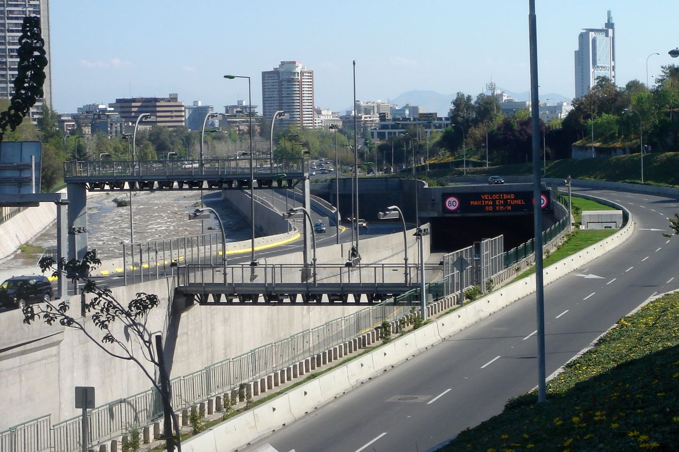 The Costanera Norte motorway curving through a cutting in central Santiago with office towers beyond