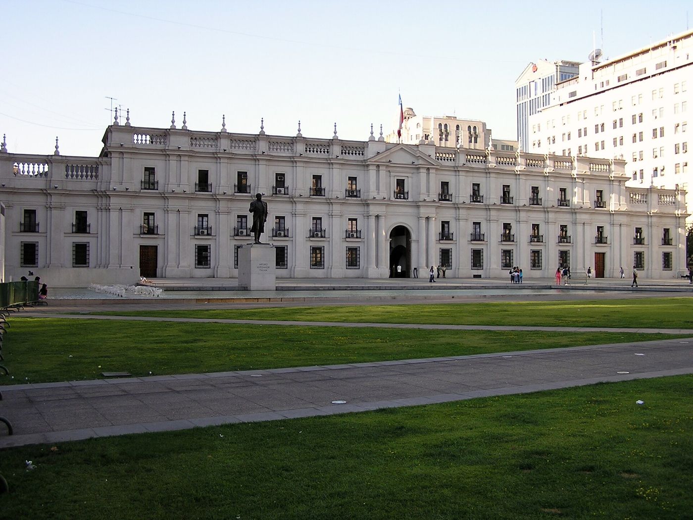 The long neoclassical facade of the Palacio de La Moneda behind a lawn under a clear sky