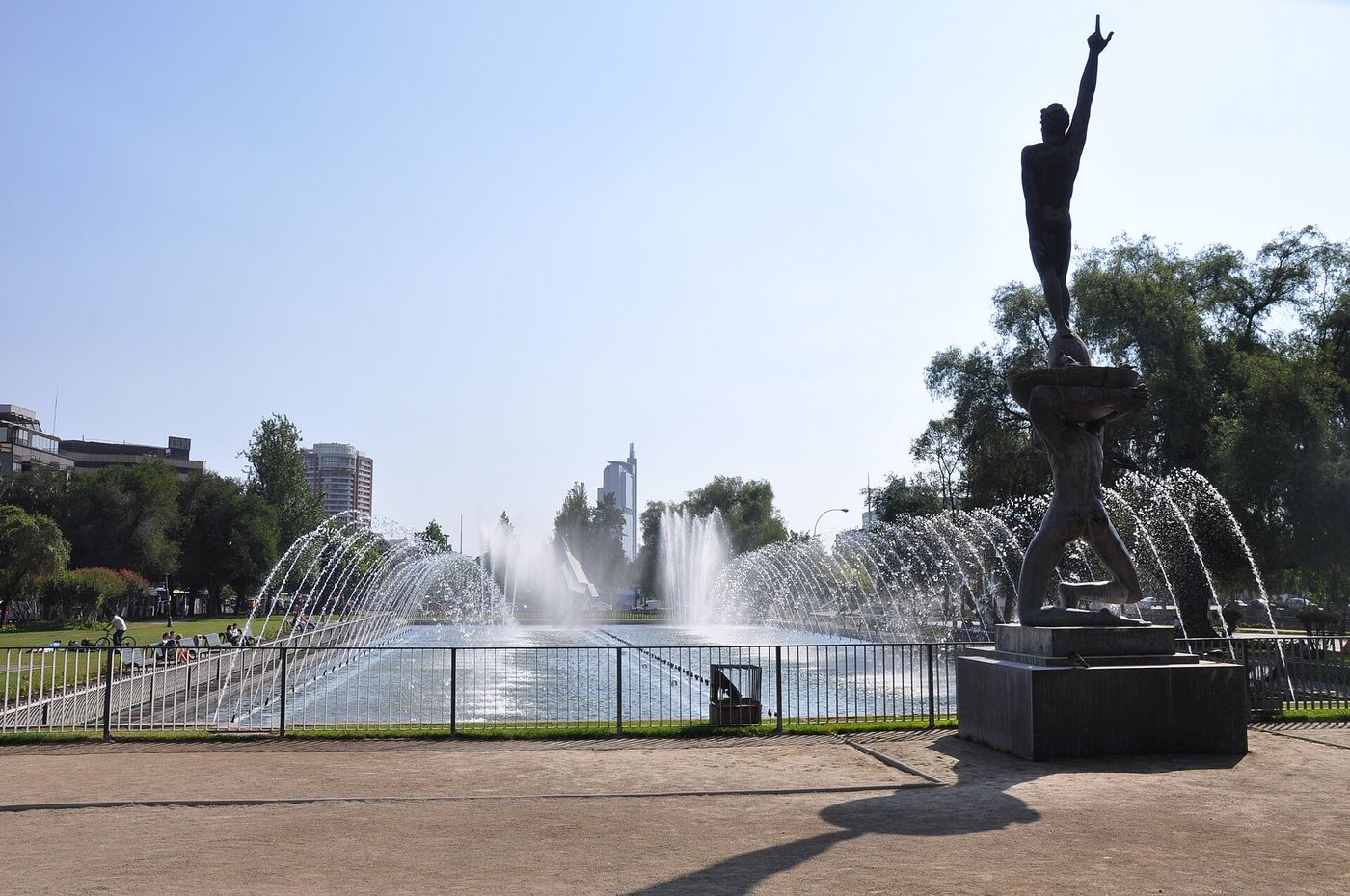 The Fuente del Bicentenario spraying water beside a bronze statue in Parque Balmaceda, with apartment towers behind