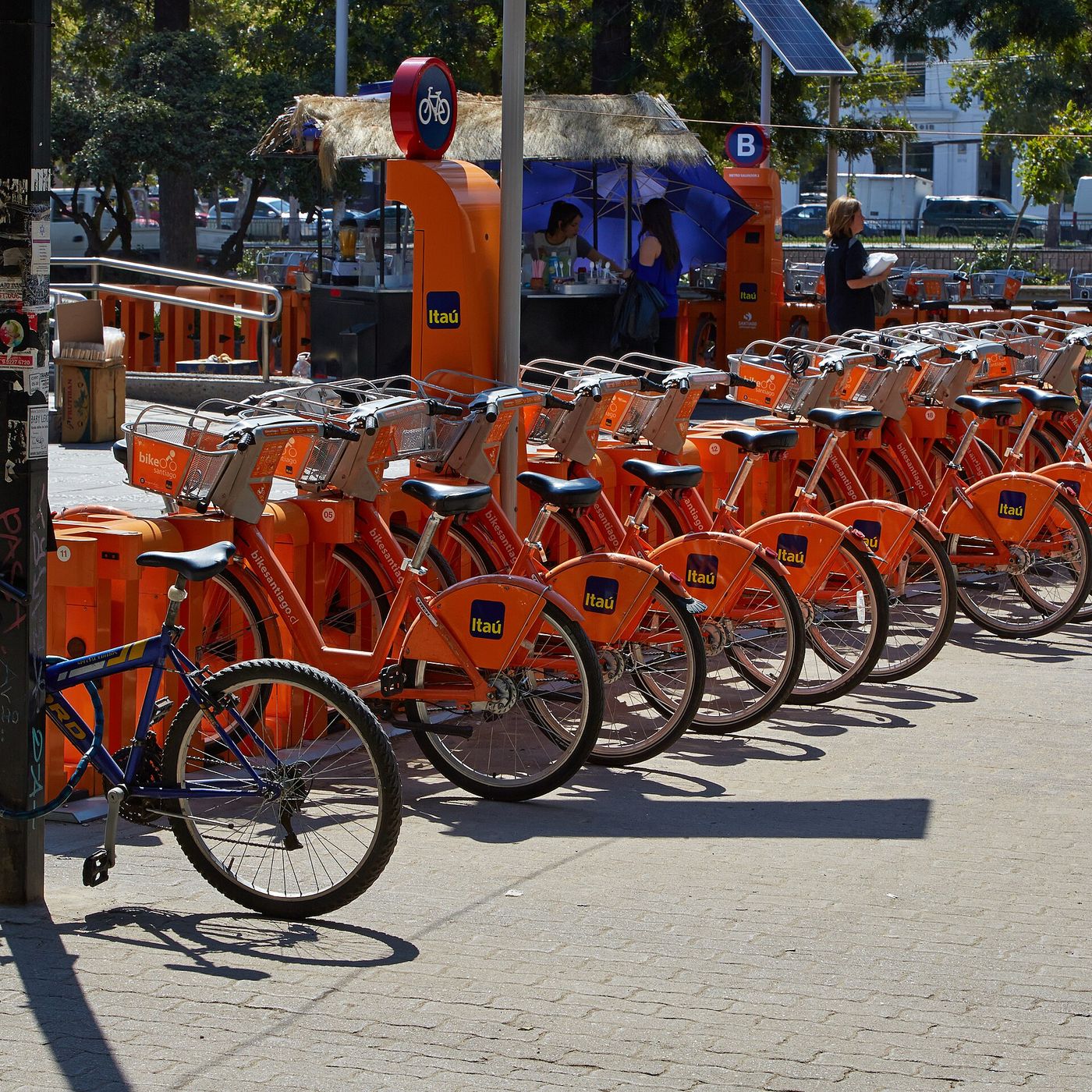 A row of orange public bike-share bicycles docked at a station in Parque Balmaceda