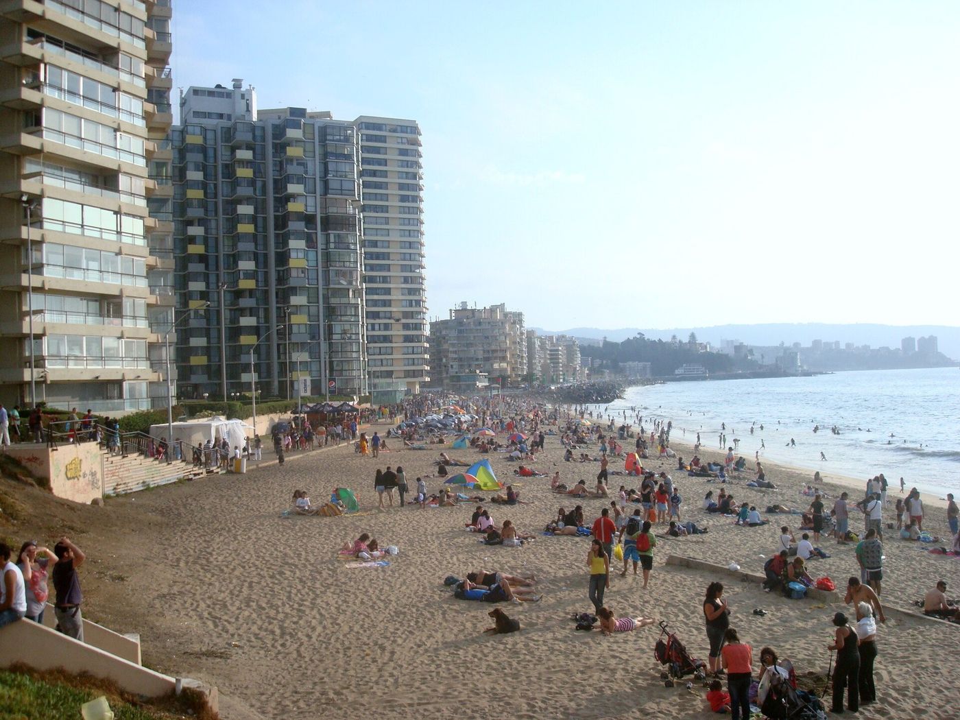 Families on Playa Acapulco in Viña del Mar below a row of tall apartment towers
