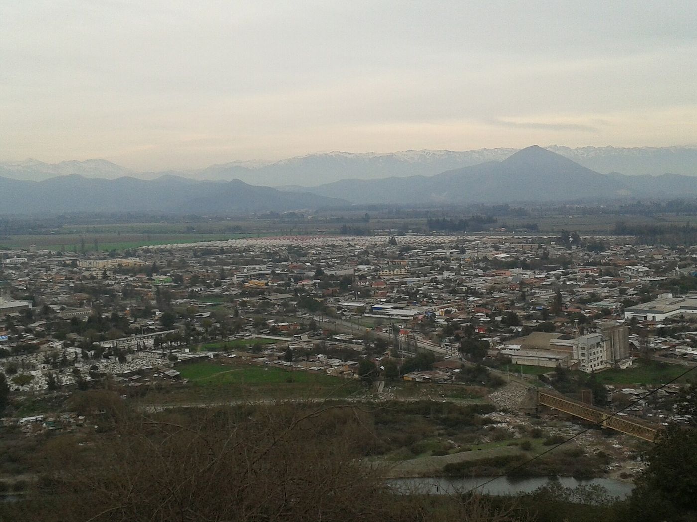 The town of Talagante spread across the valley floor in winter, with the Andes in haze behind